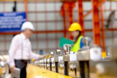 Kaskı ve güvenlik yeleği olan işçilerin bulanık geçmişine sahip makineleri vidalayın ve endüstriyel alanda tartışın ve birlikte çalışın. Mühendisler üretim fabrikasındaki makineyi inceliyor..