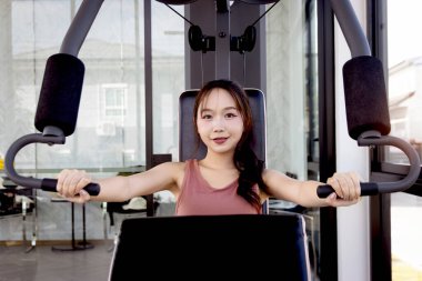 Spor aletleriyle spor yapan Asyalı güzel bir kadının portresi. Vücut geliştirme, vücut geliştirme, sağlıklı ve güçlü tutmak için vücut geliştirme ve vücut geliştirme.