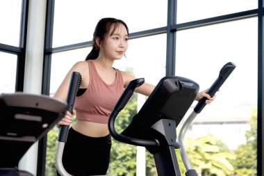 Mutlu Asyalı güzel kadın spor aletleriyle spor yapıyor. Genç gülümseyen fitness kızı egzersiz yapıyor vücudunu güçlü, zayıf, formda ve sağlıklı tutmak için antrenman yapıyor..