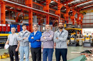 Bir grup mühendis imalat fabrikasında sıra bekliyor. Kurumsal mühendislik işçileri sanayi ortamında güvenle duruyorlar. Çeşitli profesyonel takımlar aynı yöne bakıyor..