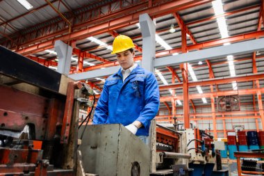 Üretim fabrikasında güvenlik kıyafeti ve kask takan erkek işçi. Endüstri üretim alanında makine ile çalışan mühendislik personeli. Endüstriyel personel fabrikada çalışıyor..
