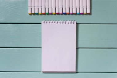 beyaz tabanlı çizimler için çok renkli işaretler ve boş beyaz sayfalı çizim defterini açmak için nane ağacından arkaplan görünümüne uzanır