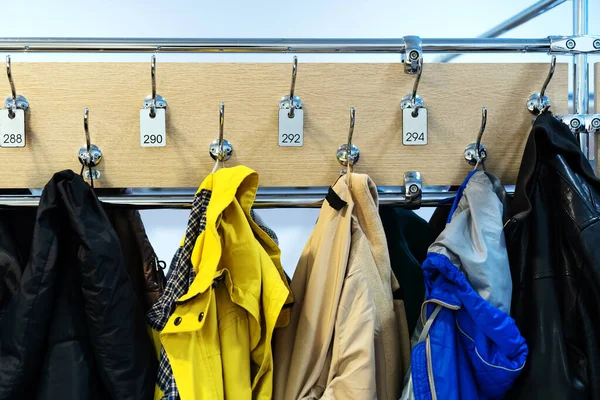 Outerwear in a public locker room of a shopping center. Things on metal hooks handed over for temporary storage.