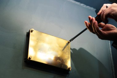 Installation of a gold colored metal plate. The process of screwing the screws into the memorial plaque clipart