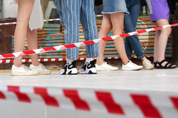 Social distance of people during a pandemic. Safety distance tape against the background of the feet of passers-by