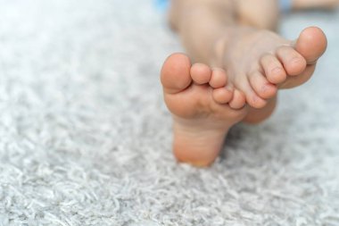 Bir gencin bacakları yumuşak halıda yatar. Rahatsız ayakkabılar giydikten sonra dinlen. Yakın plan.