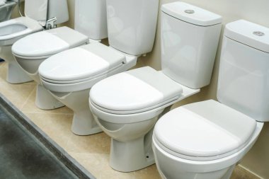Tesisatçı dükkanında bir sürü seramik tuvalet var. Tuvaletler için ekipman ticareti. Yakın plan.