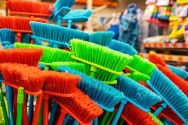 Farklı renklerde plastik süpürge. DIY mağazasındaki temizlik için geniş bir fırça çeşitliliği. Yer temizleme ekipmanı ticareti.