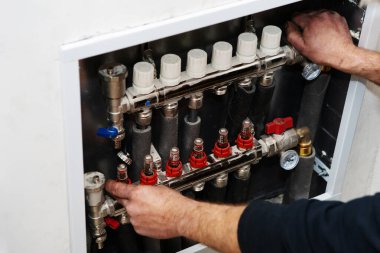 Ev ısıtma sistemi ayarlaması. Bir tesisatçı yaşam alanına otomatik şalter kuruyor. Tanımlanamayan kişi. Yakın plan.