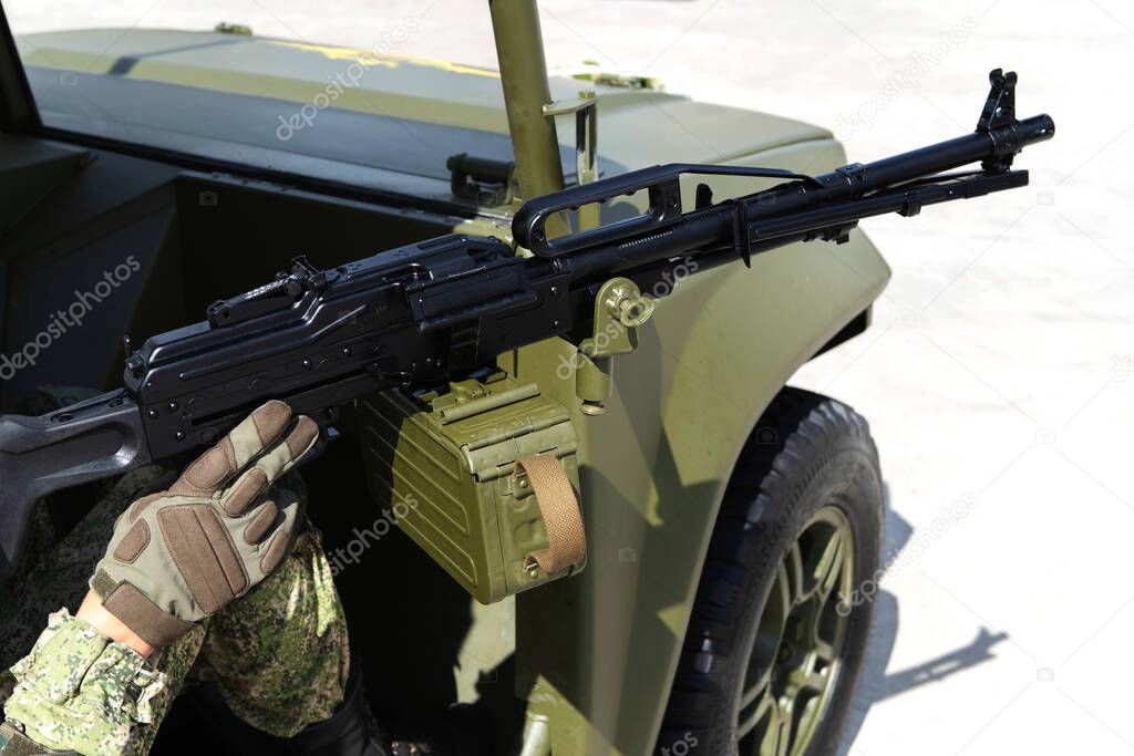 A large-caliber machine gun is installed on a military vehicle. Combat operations with the use of firearms. The soldier holds his hand on the trigger of the pistol. Cropped frame. Beyond recognition