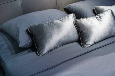 Yatağın üzerinde çeşitli gri yastıklar var. Yatak odasında yatak odası. Yakın plan.