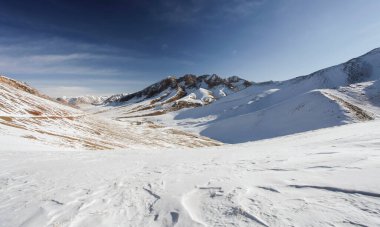 Karla kaplı bir dağ geçidinden kış manzarası. Kasım 'da Asya dağlarındaki bir geçitten geçen toprak yol.. 