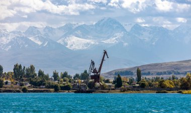 Dağların arka planındaki Issyk-Kul Gölü 'ndeki Przhevalsk iskelesinin vinçleri. Issyk-Kul Gölü 'nün doğu kıyısının manzarası.. 