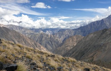 Bir sonbahar günü Asya dağlarının üzerindeki bulutlu gökyüzü manzarası. Tien Shan 'da dik yamaçları, kayaları ve geçitleri olan dağ manzarası..