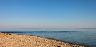 Baykal Gölü 'nün Panorama' sı bir yaz günü bir teknede balıkçılarla. Suyun mavi yüzeyi Haziranda bir balıkçı teknesinin silueti ile.