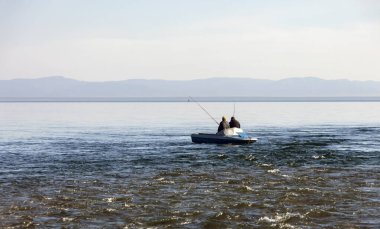 Baykal Gölü 'ndeki nehrin birleştiği noktada iki balıkçı tekneden balık tutuyor. Kayıkla manzara ve nehirde iki adam Baykal Gölü 'ne akıyor..