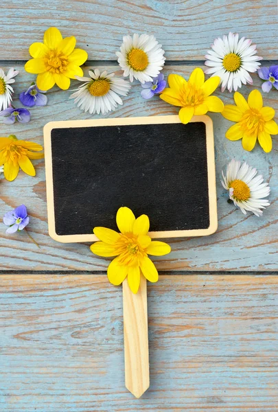 Placa de giz preto vazio em um velho usado de madeira azul, cinza atado com margaridas e borboletas primavera e verão para uma serena atmosfera alegre flores — Fotografia de Stock