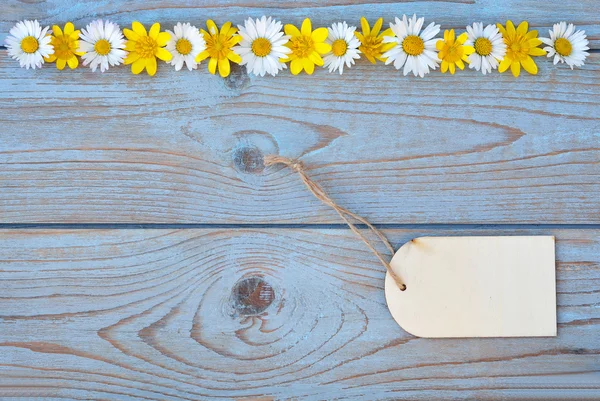 Old blue grey wooden background with label and a row of buttercups and daisies field flowers with a empty space for text — Stock Photo, Image