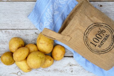 Vintage mavi mutfak çay havlu boş kopya alanı ile bir eski yıpranmış ahşap beyaz raflar zemin üzerine jüt çuval içinde organik taze Çiğ patates