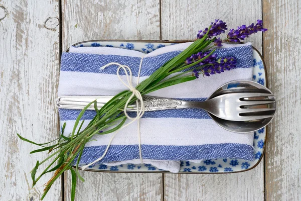 silver cutlery and a blue white napkin kitchen towel with lavender decoration and empty copy space in rustic vintage country style