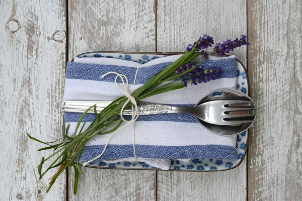 silver cutlery and a blue white napkin kitchen towel with lavender decoration and empty copy space in rustic vintage country style