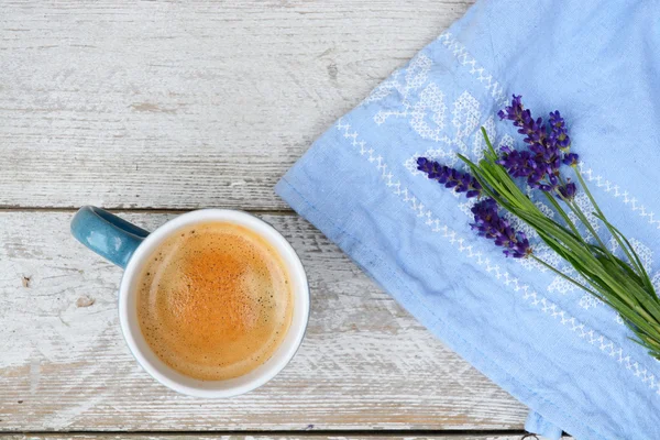 Blue coffee cup on a old white wooden shelves background with lavender flowers and kitchen towel and empty copy space. — Stock Photo, Image