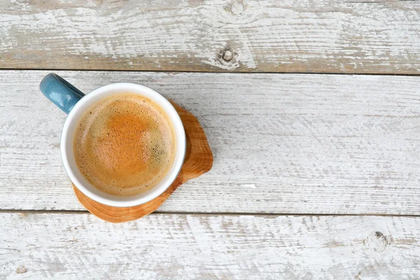 Antiguo fondo de estantes de madera blanca con una taza de café azul con crema de café y espacio de copia vacío — Foto de Stock