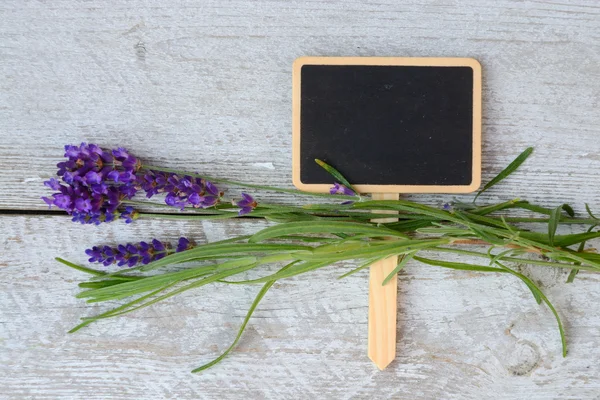 Branco cinza velho prateleiras de madeira fundo com placa de giz vazio e espaço de cópia e flores de lavanda decoração — Fotografia de Stock