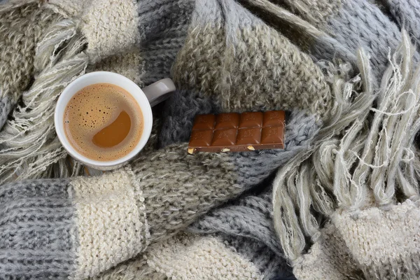 Hot chocolate in coffee mug  with a grey, ivory, ecru knitted scarf around it and chocolate bar — Stock Photo, Image