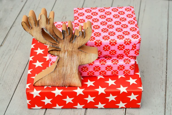 Patrón de flores estrella roja y rosa regalos de Navidad con renos de madera sobre un fondo de estantes de madera — Foto de Stock