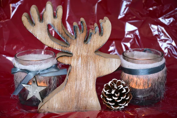 Fondo blanco rojo de Navidad con candelabros de té decorados con un reno de madera, cono de pino y bola de Navidad — Foto de Stock