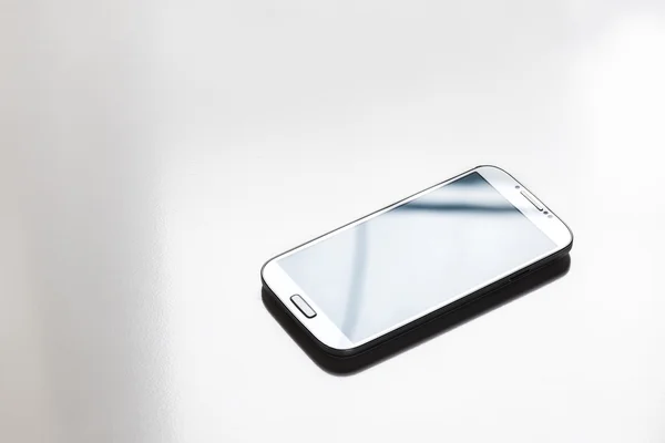 Smartphone blanc sur un bureau blanc — Photo
