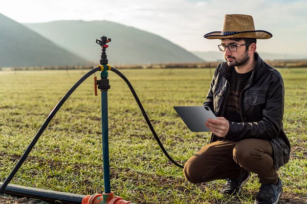 Smart farming agriculture concept. Man hands holding tablet on blurred organic farm as background. Smart irrigation technology. american farmer concept