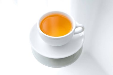 Beyaz porselen bir fincanın yatay fotoğrafı. Bir fincan yeşil çay, bir ayna masası, bir yansıma.