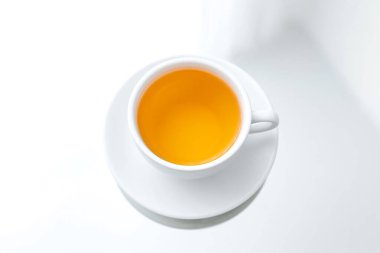 Beyaz porselen bir fincanın yatay fotoğrafı. Bir fincan yeşil çay, bir ayna masası, bir yansıma.