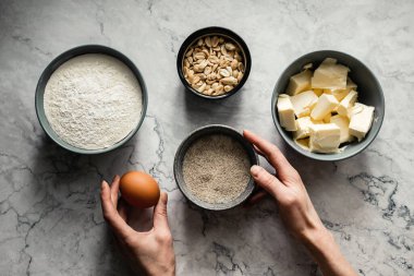 Kurabiye pişirmek için gerekli malzemeler. Un, şeker, vanilya, tuz, tereyağı, fıstık, yumurta. Üst görünüm yatay fotoğraf, mermer zemin