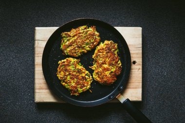 Kızartma tavasında sebzeli kabak ve havuçlu börek ve ahşap kesim tahtası.