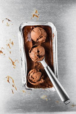 Bir kutu çikolatalı dondurma ve bir kepçe, birkaç top, üst manzara.