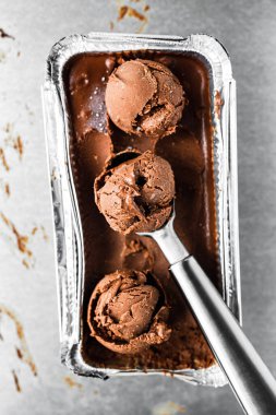 Bir kutu çikolatalı dondurma ve bir kepçe, birkaç top, üst manzara.