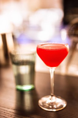 Bardaki coupe bardağında parlak kırmızı bir alkollü kokteyl. Sığ bir alan derinliğine sahip bir yaşam tarzı fotoğrafı.