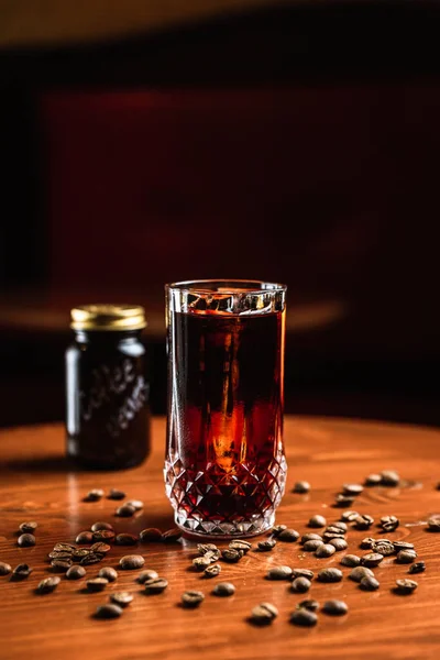バーでは アイススピアー コーヒー豆の周りにあるコリンズのハイボールガラスのカクテル 言葉のあるガラス瓶コーヒー豆それに木製のテーブルの上に — ストック写真