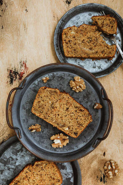 Вертикальное изображение сверху морковного яблочного орехового пирога. Кусочки торта на винтажных металлических пластинах, деревянный фон. 