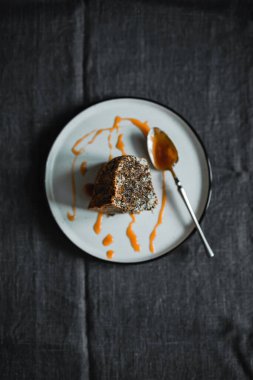 A slice of poppy seed bundt cake on a plate served with salted caramel