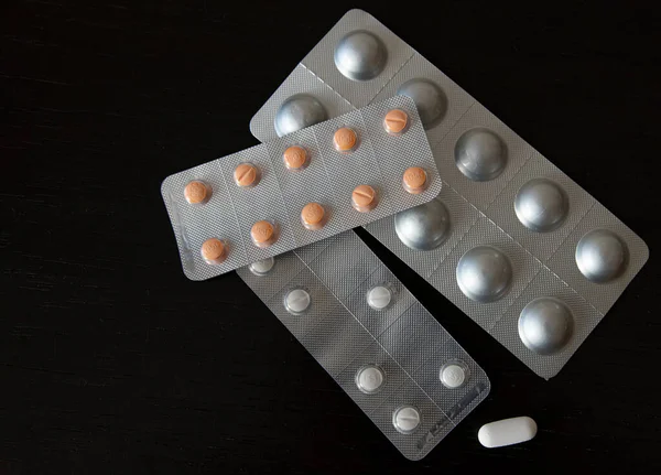Karanlık bir arka planda çeşitli ilaç ve kapsüllerle dolu bir yığın su topladı. İlaç endüstrisi konsepti. Eczacılık firması. Antibiyotik direnci.