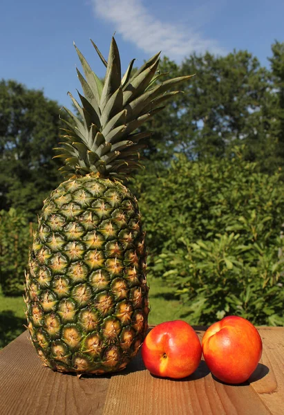 Ekologické čerstvé ananas a broskve venku na stole na farmářském trhu — Stock fotografie