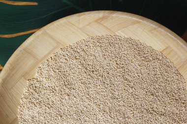 Bambu hasırında yaprak olan bir kase pişmemiş Millet.