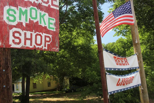 Smoke Shop Sign Next to Beer and Liquor sign with American Flag. Rural Texas Scenery. Small Town Texas