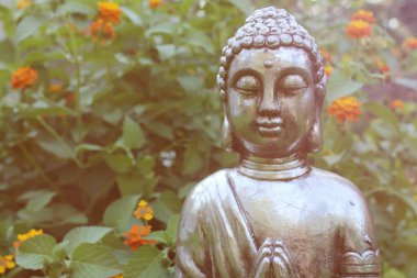 Arka planda yeşil bitkiler olan, Bahçedeki Buda Heykeli