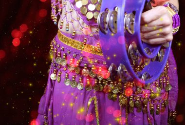 Göbek Dansçısı mor dans kostümü giyiyor. Renkli bokeh ile yakın plan.