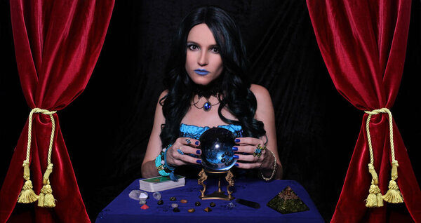 Экстрасенс с хрустальным мячом и карточками Таро с красными бархатными занавесками